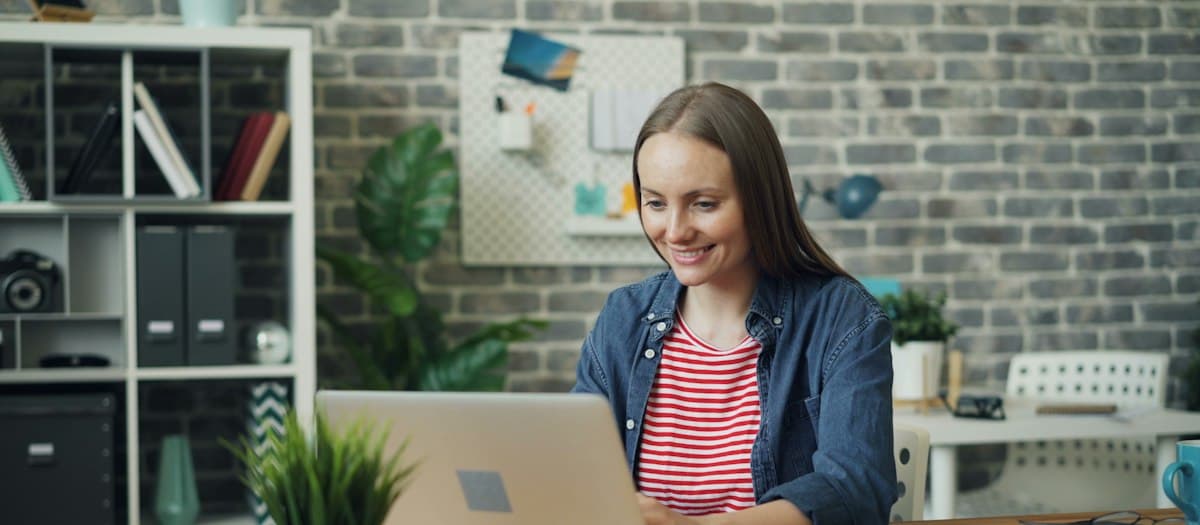 Mujer trabajando en su laptop desde un escritorio de oficina
